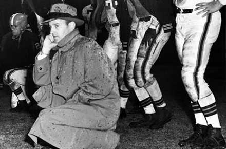 Paul Brown and players on sideline in the rain, 1952