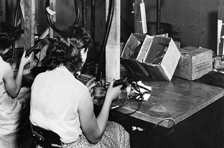 Women employees at Clark Cable Corporation solder wire harnesses by hand, 1952.